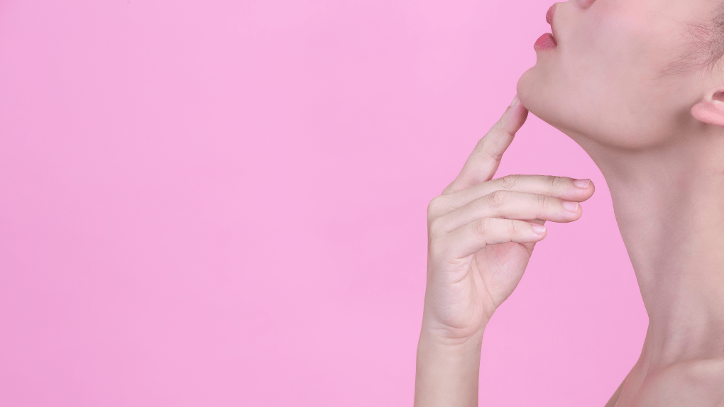 beautiful young woman is touching her chin with her index finger pink wall 1 edited