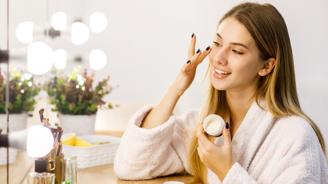 young beautiful blonde girl cares face skin with moisturizer front mirror edited